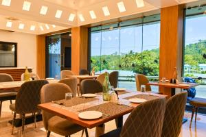un restaurante con mesas, sillas y ventanas grandes en Beyond Blu, en Port Blair