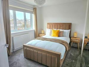 a bedroom with a bed with yellow pillows and a window at Family Home with Free Parking in Newton Mearns