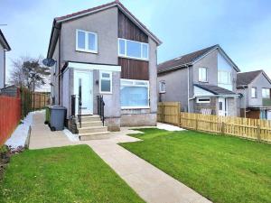 a house with a fence and a grass yard at Family Home with Free Parking in Newton Mearns