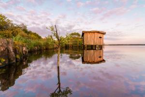 a wooden out house in the middle of a body of water at Ferienwohnung Hohner Seeblick in Hohn
