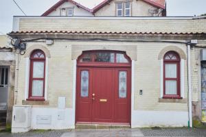 eine rote Tür in einem Gebäude mit drei Fenstern in der Unterkunft Maison214 in Vila Nova de Gaia