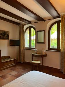 a bedroom with a bed and a table and windows at Le Château du Landsberg in Barr