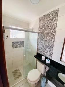 a bathroom with a toilet and a glass shower at Apartamento em Ubatuba - Condomínio Ville II - 300 metros da Praia do Sapê - Maranduba in Ubatuba