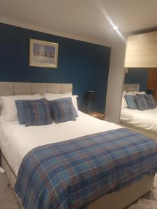 a bedroom with two beds and a blue wall at Delny Muir House in Invergordon
