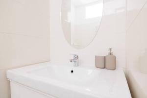 La salle de bains blanche est pourvue d'un lavabo et d'un miroir. dans l'établissement Modern Apartment near City Center - 2BR, Netflix, à Vienne