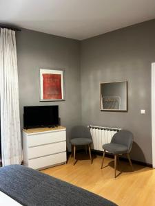 a bedroom with two chairs and a tv and a dresser at Hostal San Martin in León