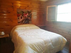 um quarto com uma cama num chalé de madeira em Cabaña Oregones del Valle em Mendoza
