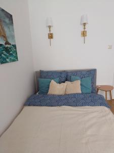 uma cama com almofadas azuis e brancas num quarto em Apartament Turkusowy em Gdansk