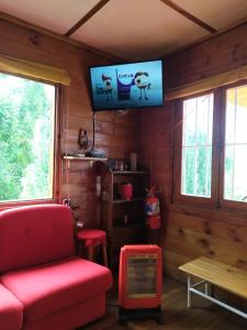 uma sala de estar com um sofá vermelho e uma televisão de ecrã plano em Cabaña Oregones del Valle em Mendoza