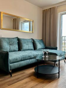 ein Wohnzimmer mit einem grünen Sofa und einem Tisch in der Unterkunft Apartament Złotowłosa przy Księżym Młynie Zupełnie NOWY!!! PARKING podziemny gratis!!! in Łódź