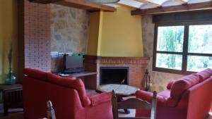 sala de estar con 2 sillas rojas y chimenea en Cortijo los Bataneros, en Segura de la Sierra