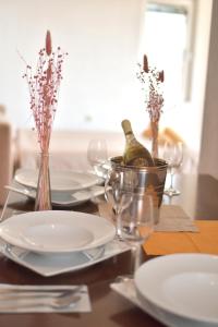 einen Tisch mit weißen Tellern und eine Flasche Wein in der Unterkunft Villa Marto Old Town Ohrid in Ohrid