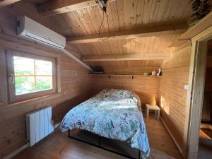 ein Schlafzimmer in einem Blockhaus mit einem Bett darin in der Unterkunft Le Chalet « au Fil de l’eau » 