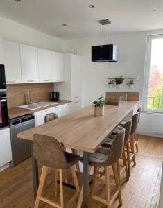 uma cozinha com uma grande mesa de madeira e cadeiras em Maison de ville avec terrasse 4 à 6 personnes em Lion-sur-Mer