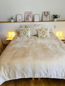um quarto com uma grande cama branca com almofadas em Maison de ville avec terrasse 4 à 6 personnes em Lion-sur-Mer