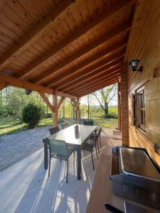 eine Terrasse mit einem Tisch, Stühlen und einem Grill in der Unterkunft Le Chalet « au Fil de l’eau » 