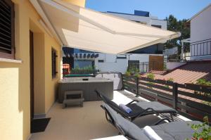 eine Terrasse mit einem Tisch und einem weißen Sonnenschirm in der Unterkunft Studio für 4 Personen ca 40 qm in Njivice, Kvarner Bucht Krk in Njivice