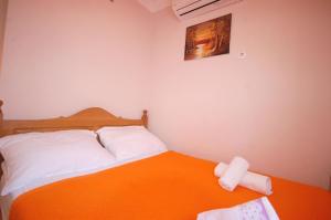ein kleines Schlafzimmer mit einem Bett mit einer orangefarbenen Decke in der Unterkunft Studio für 4 Personen ca 40 qm in Njivice, Kvarner Bucht Krk in Njivice