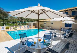 a patio with a table and umbrella next to a pool at Hotel Doce Mar in Búzios