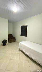 a white bedroom with a bed and a couch at Casa aconchego in Feira de Santana