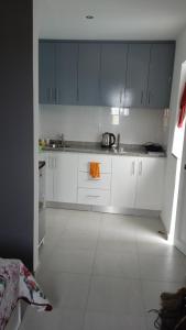 una cocina con armarios blancos y una toalla naranja en Casa Mrichica en Mão para Trás