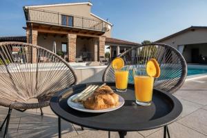 een tafel met een bord eten en twee glazen sinaasappelsap bij Ferienhaus mit Privatpool für 7 Personen ca 200 qm in Loborika, Istrien Südküste von Istrien in Loborika