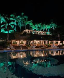 een zwembad met tafels en stoelen in een resort 's nachts bij Apartamento completo em Resort in Represa Capivari
