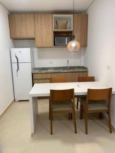 eine Küche mit einem Tisch und Stühlen sowie einem Kühlschrank in der Unterkunft Apartamento completo em Resort in Represa Capivari