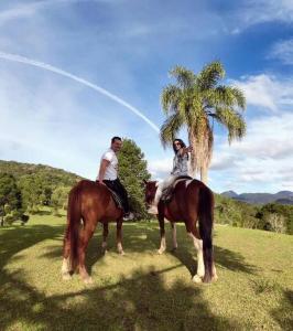 zwei Menschen reiten auf Pferden neben einer Palme in der Unterkunft Apartamento completo em Resort in Represa Capivari