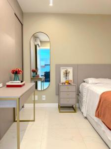Schlafzimmer mit einem Bett, einem Schreibtisch und einem Spiegel in der Unterkunft Conforto e Sofisticação a poucos metros da Orla in Vila Velha