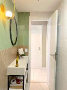 ein Bad mit einem Waschbecken und einer Dusche mit einem Spiegel in der Unterkunft Conforto e Sofisticação a poucos metros da Orla in Vila Velha