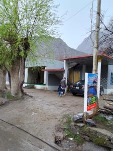 une personne debout devant un bâtiment avec un panneau dans l'établissement Pine tree resort upper kachura lake road, à Skardu