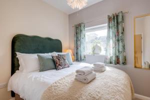 a bedroom with a large bed with towels on it at Stylish Modern Town Centre Flat in Carterton