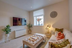 a living room with a couch and a clock on the wall at Stylish Modern Town Centre Flat in Carterton