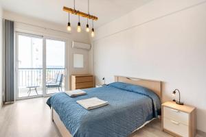 a bedroom with a blue bed and a balcony at Must Stay - Finikoudes Seaview in Larnaka