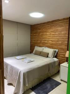Pajuçara Front Beach في ماسيو: غرفة نوم بسرير مع جدار خشبي