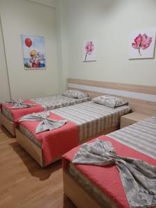 three beds in a room with red sheets at Apartment Eclipse in Sarandë