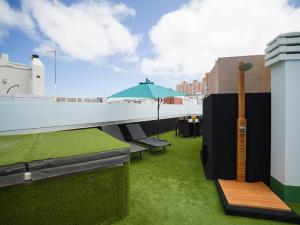 a rooftop patio with an umbrella and green grass at Ferienwohnung für 2 Personen ca 28 qm in Las Palmas de Gran Canaria, Gran Canaria Nordküste Gran Canaria in Las Palmas de Gran Canaria