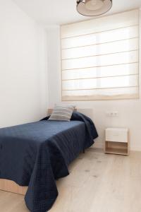 a bedroom with a bed with a blue blanket and a window at Koala21 - Apartamento céntrico y moderno con Parking in Jaén +12 photos
