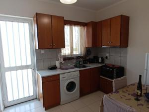a kitchen with wooden cabinets and a washing machine at G.S. Studio 2 in Mastihari