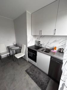 a kitchen with a stove and a sink and a table at Apartament Zalew Siemianówka in Michałowo