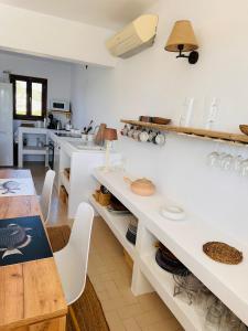 uma cozinha com balcões brancos e uma mesa com cadeiras em Minorque maison 4 chambres - licence touristique em Son Bou