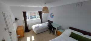 a bedroom with two beds and a desk and a window at Unique house with up to 3 self contained living areas in Bournemouth