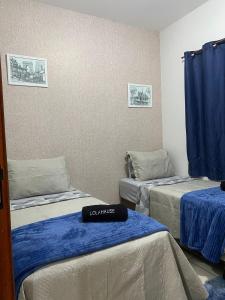 - une chambre avec 3 lits dans une chambre avec des rideaux bleus dans l'établissement lolahouse, à Monte Sião