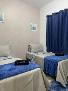 - 3 lits dans une chambre dotée de rideaux bleus dans l'établissement lolahouse, à Monte Sião