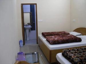 two beds in a room with a mirror and a sink at OM Kutir Badrinath Dham in Badrīnāth