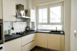 eine Küche mit weißen Schränken, einem Waschbecken und einem Fenster in der Unterkunft ophelia apartment in Rom