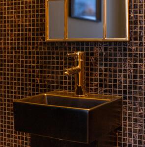 ein Waschbecken mit einem Wasserhahn und einem Spiegel in der Unterkunft White Brig Guesthouse in Hudiksvall