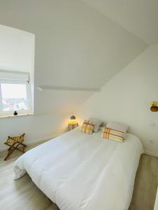 - une chambre blanche avec un grand lit blanc et 2 oreillers dans l'établissement Lou & Moi Appartement à 50m de la plage, à Cayeux-sur-Mer