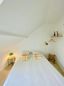 um quarto com uma grande cama branca e 2 almofadas em Lou & Moi Appartement à 50m de la plage em Cayeux-sur-Mer